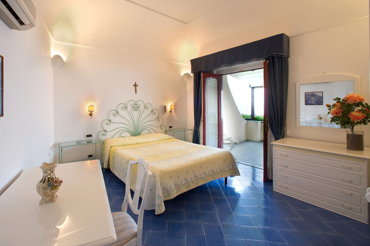 A bedroom with a bed, bedside tables, a dresser, a chair, and a window with curtains.