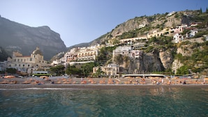 Privat strand, sort sand, solsenger og parasoller