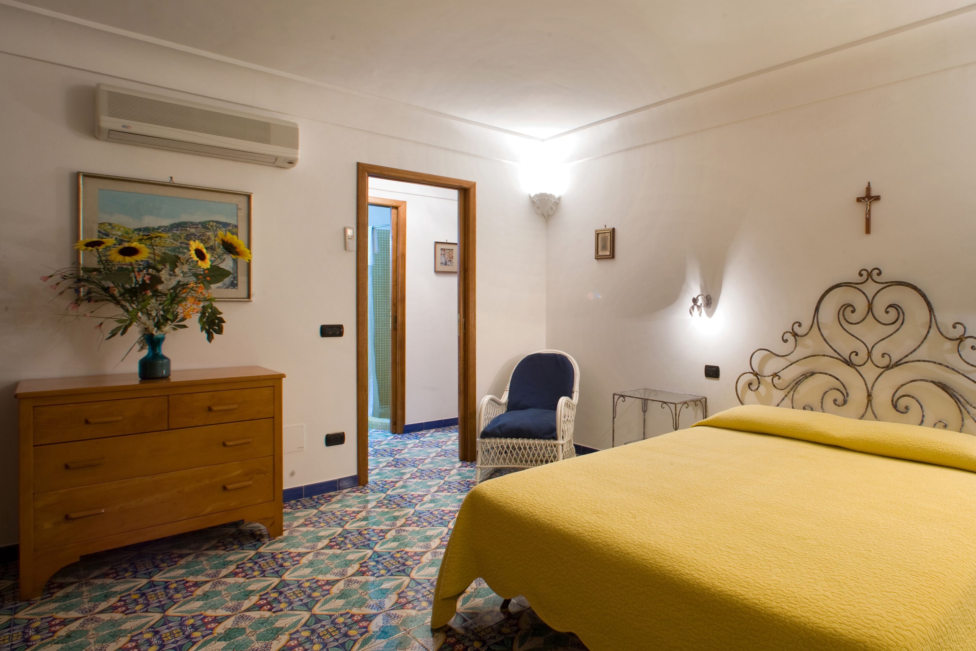A bedroom with a bed, a dresser, a chair, and a painting.