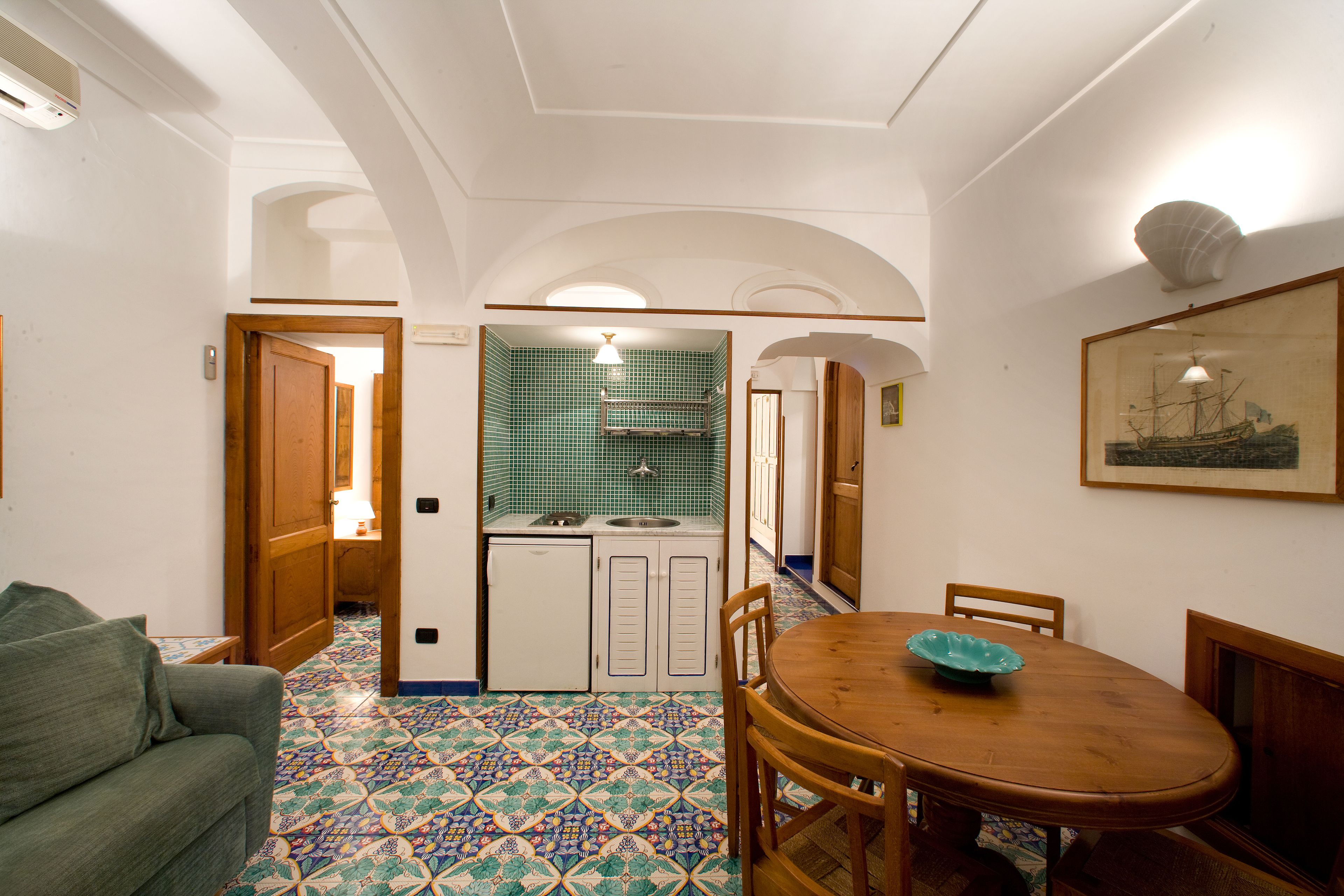 A dining area with a wooden table and chairs, a green bowl, and a tiled floor.