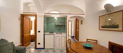 A dining area with a wooden table and chairs, a green bowl, and a tiled floor.