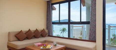Una sala de estar moderna con un sofá, una mesa de centro con fruta y un ventanal con vista al mar.