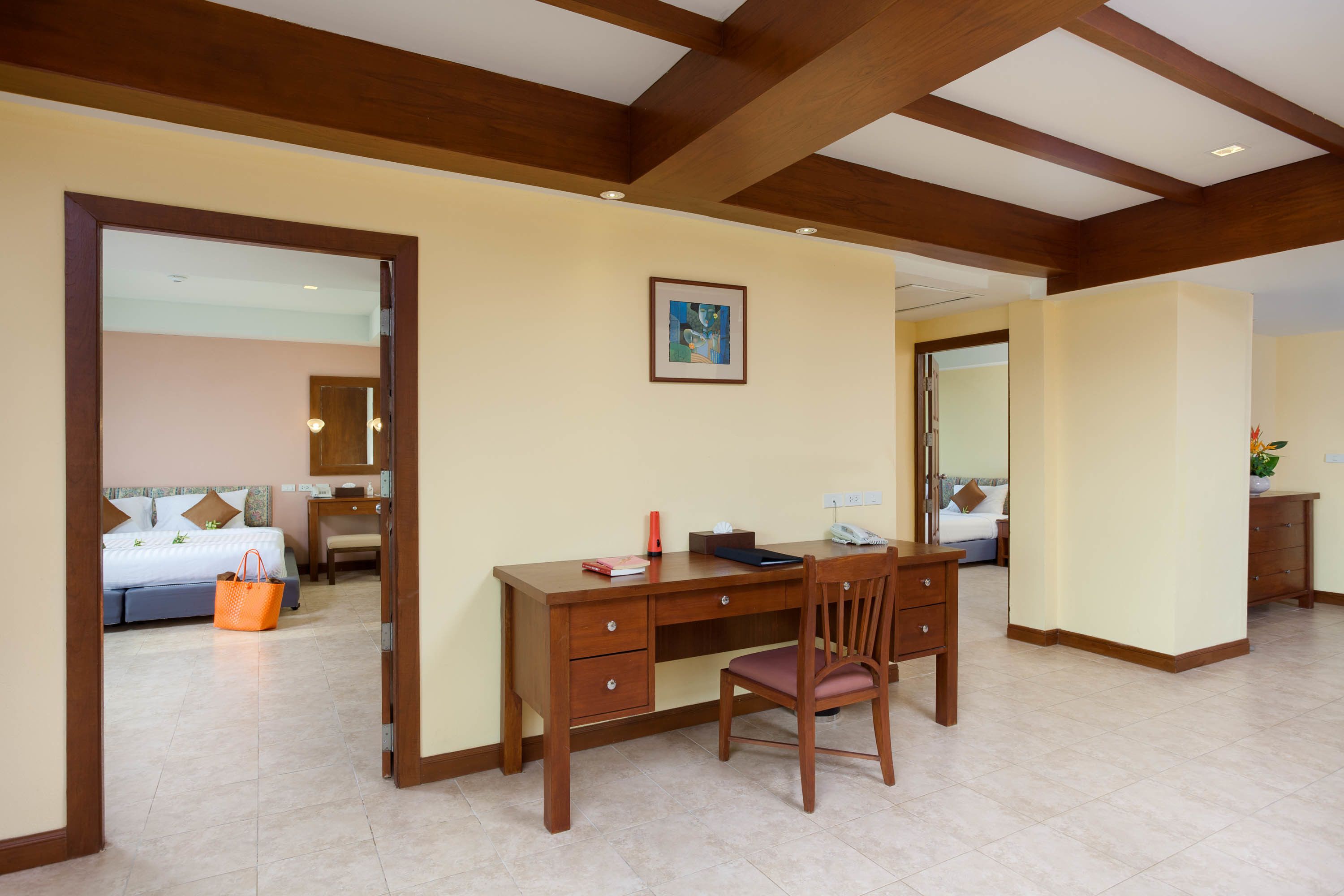 Habitación de hotel con escritorio de madera, una silla, una cama y un baño visible a través de una puerta abierta.
