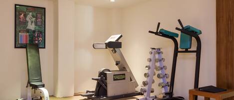 A fitness room with a rowing machine, a stationary bike, and a weight bench.
