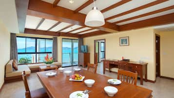 Un comedor amplio con una mesa de madera dispuesta para una comida, un sofá con vistas y un televisor al fondo.