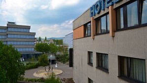 A hotel building with a sign that reads "HOTEL" in blue letters. There is a roundabout with a statue in the center, and a parking lot is visible. - Fair Hotel am Rathaus (Schwalbach am Taunus)
