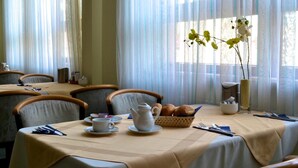 A dining area with tables set for breakfast, including bread, pastries, and a teapot. - Fair Hotel am Rathaus (Schwalbach am Taunus)