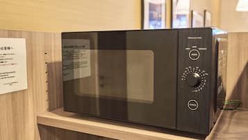 A microwave oven with a digital display and control panel, placed on a wooden countertop.