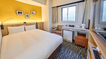 Una habitación de hotel con una cama grande, un escritorio, una silla, un refrigerador pequeño y una ventana con cortinas.