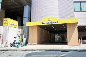 The entrance to Smile Hotel with a large yellow sign featuring a smiley face. - Smile Hotel Tokyo Asagaya (Tokyo)