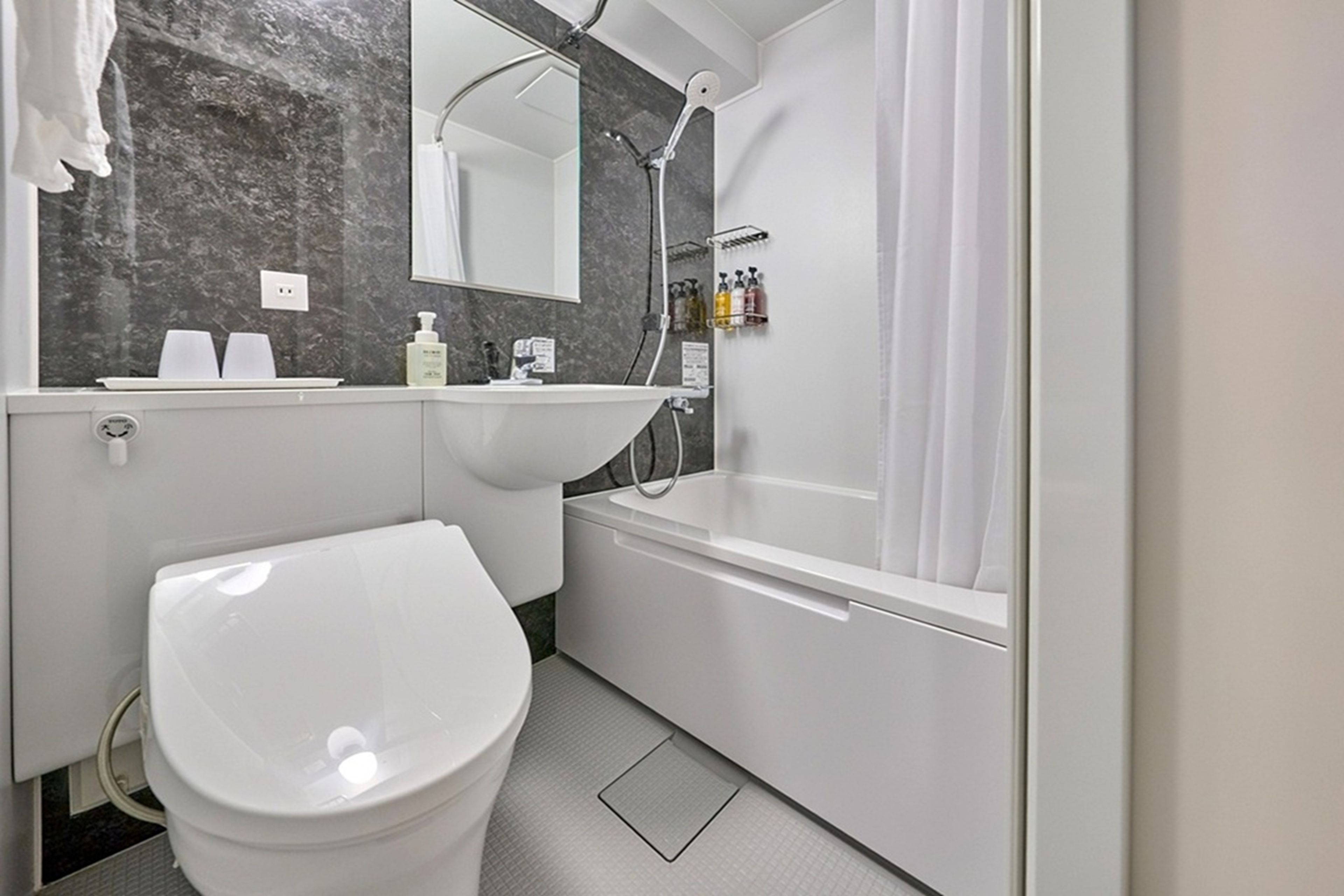 A modern bathroom with a white toilet, a sink, and a shower area.