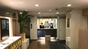 A reception area with a reception desk, a clock, and a plant. - Smile Hotel Tokyo Asagaya (Tokyo)