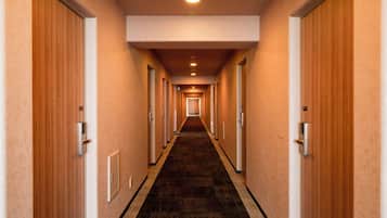 A hotel corridor with doors on both sides, a carpeted floor, and a ceiling light.