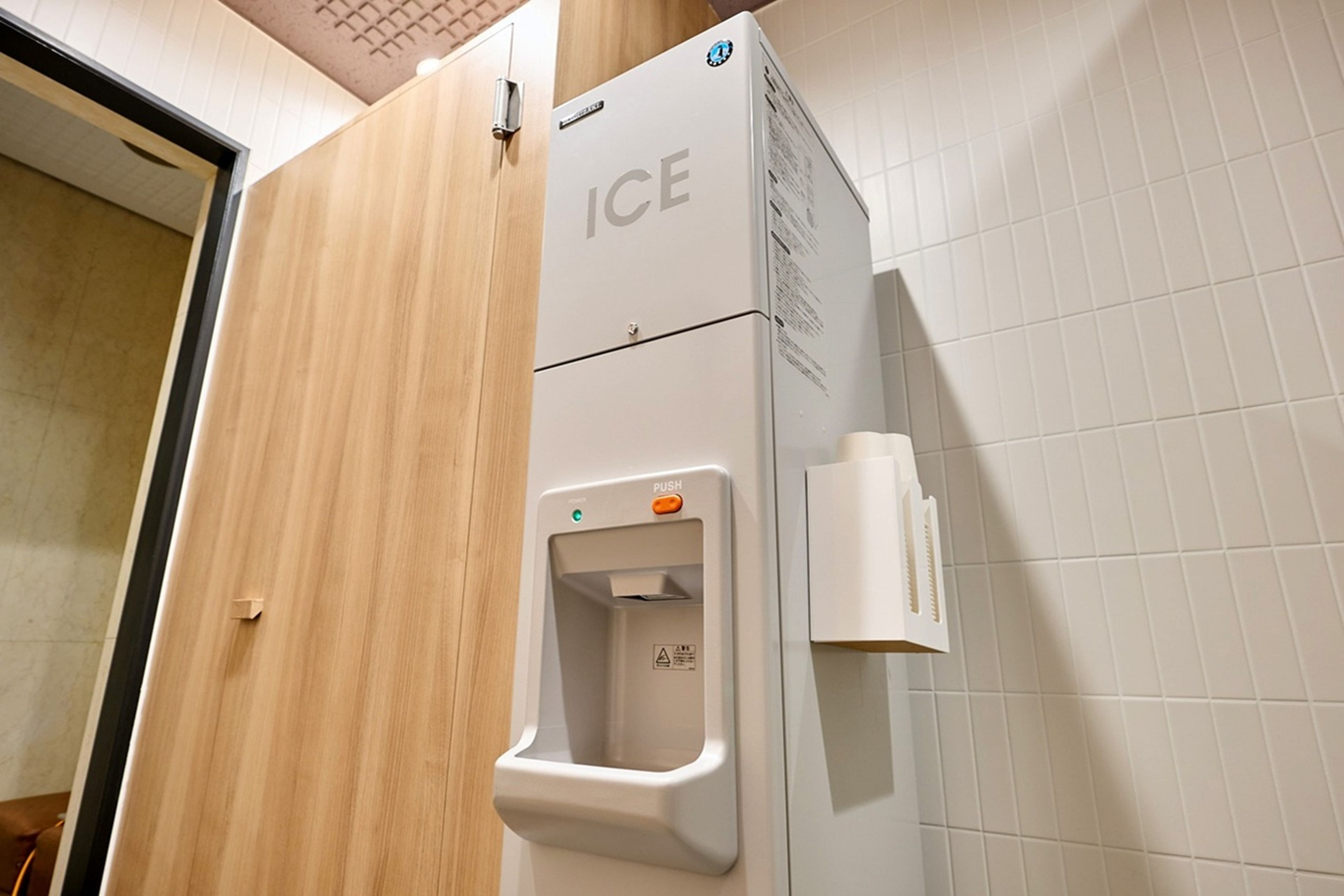 Un baño con dispensador de hielo empotrado en la pared y dispensador de toallas de papel.