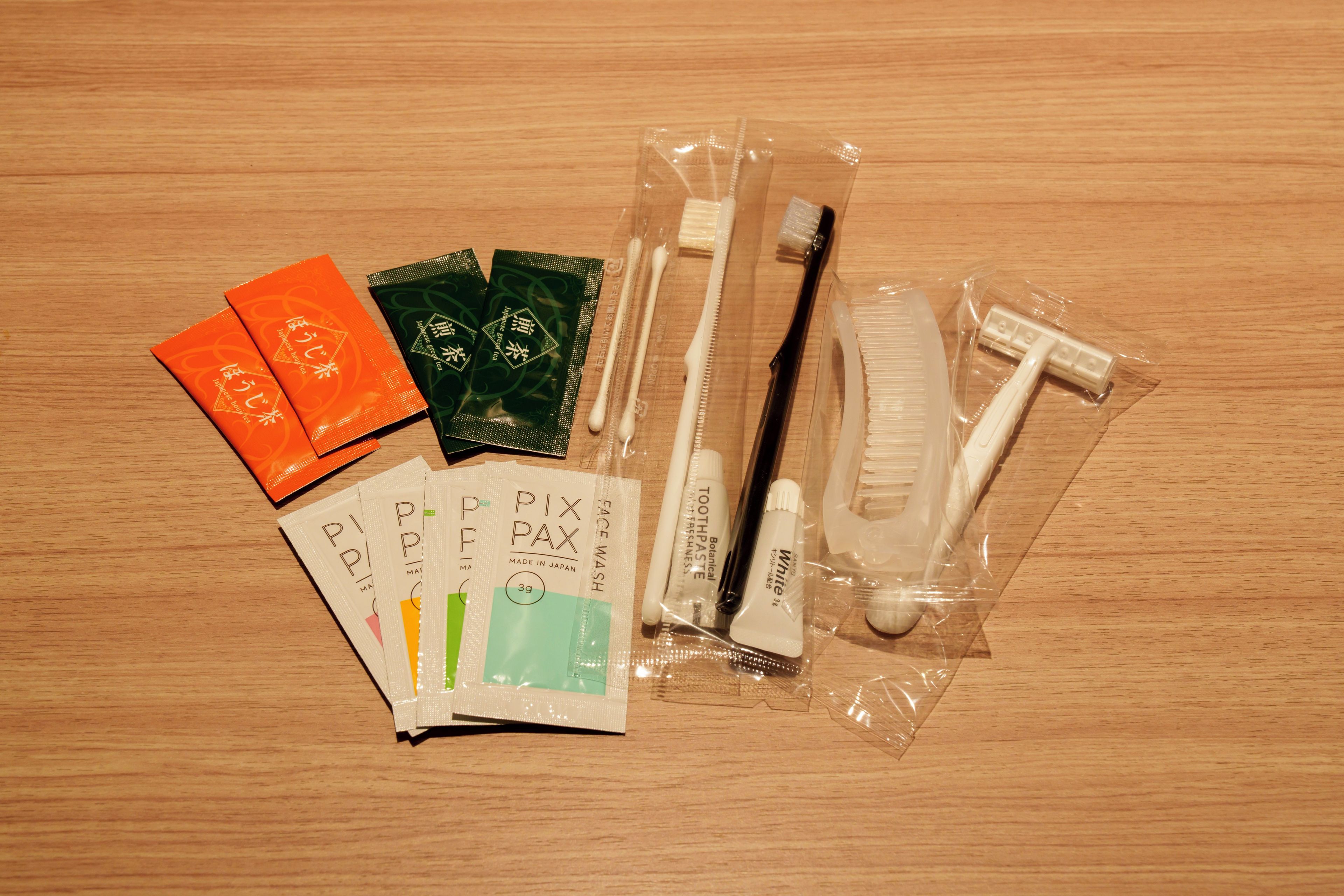 A variety of personal care items, including toothbrushes, toothpaste, and dental floss, all packaged and laid out on a wooden surface.