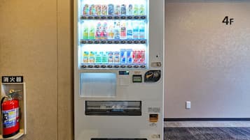 Máquina expendedora con diferentes bebidas y aperitivos, un extintor y el número de pared '4F'.