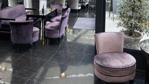 A modern indoor seating area with black-tiled floors, purple upholstered chairs, and hanging pendant lights. - Maison Albar - Le Diamond (Paris)