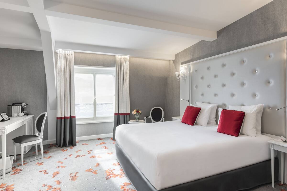 A modern hotel room with a large bed, a desk, and a chair.