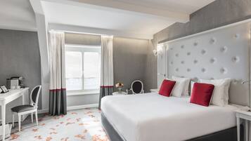 A modern hotel room with a large bed, a desk, and a chair.