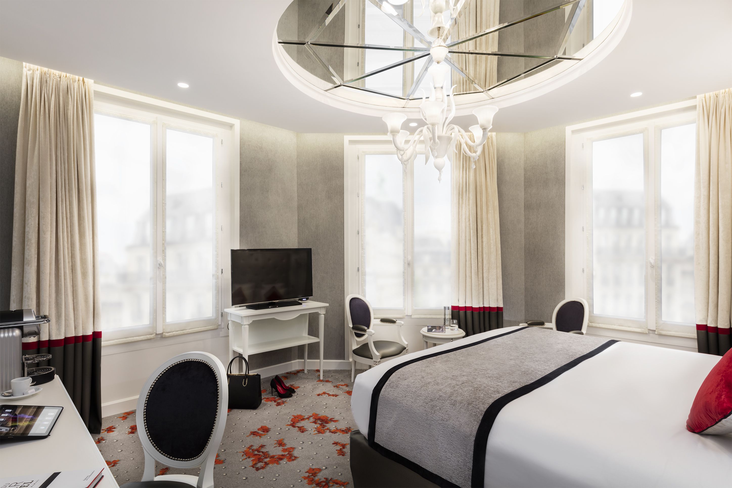 Una habitación de hotel con una cama grande, un escritorio con televisor, una silla y una mesita.