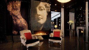 A luxurious lobby with two ornate armchairs, a large wall mural, a fireplace, and a chandelier. - Maison Albar - Le Diamond (Paris)
