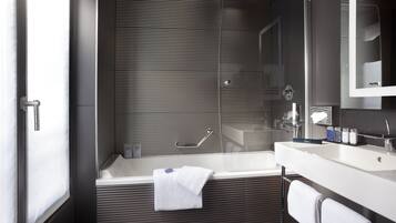 Une salle de bain moderne équipée d’une baignoire, d’une douche et d’un meuble-lavabo avec un miroir.