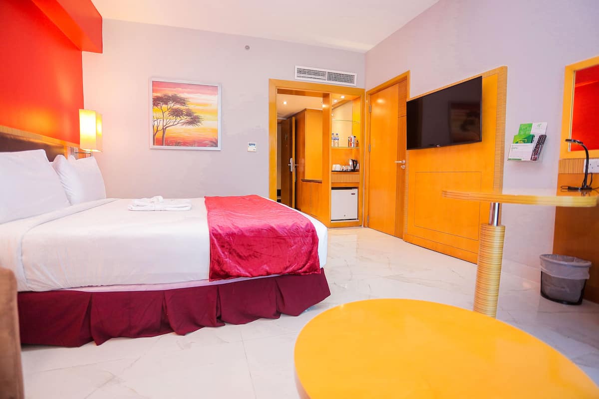 A hotel room with a bed, a television, a desk, and a bathroom visible through an open door.