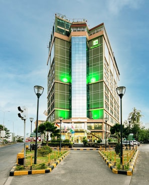A modern hotel with a prominent glass facade, a central entrance, and a well-maintained outdoor area with a paved walkway and street lamps. - Holiday Inn Dar Es Salaam City Center by IHG (Dar es Salaam)