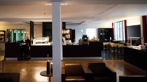 Un hall d’hôtel moderne doté d’un bar, de coins salon et d’un comptoir d’accueil.
