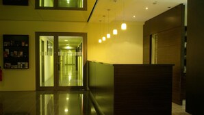 Un espace d’accueil moderne doté d’une porte d’entrée en verre, d’un comptoir de réception et d’un couloir menant à d’autres pièces.