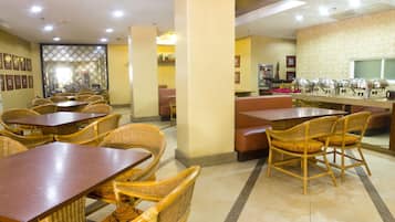 A restaurant with wicker furniture, a counter with food service equipment, and a patterned wall.