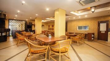 A restaurant with wicker chairs, a wooden table, and a patterned wall.