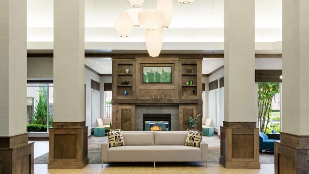 Un amplio salón con chimenea, un sofá color beige y una lámpara moderna.