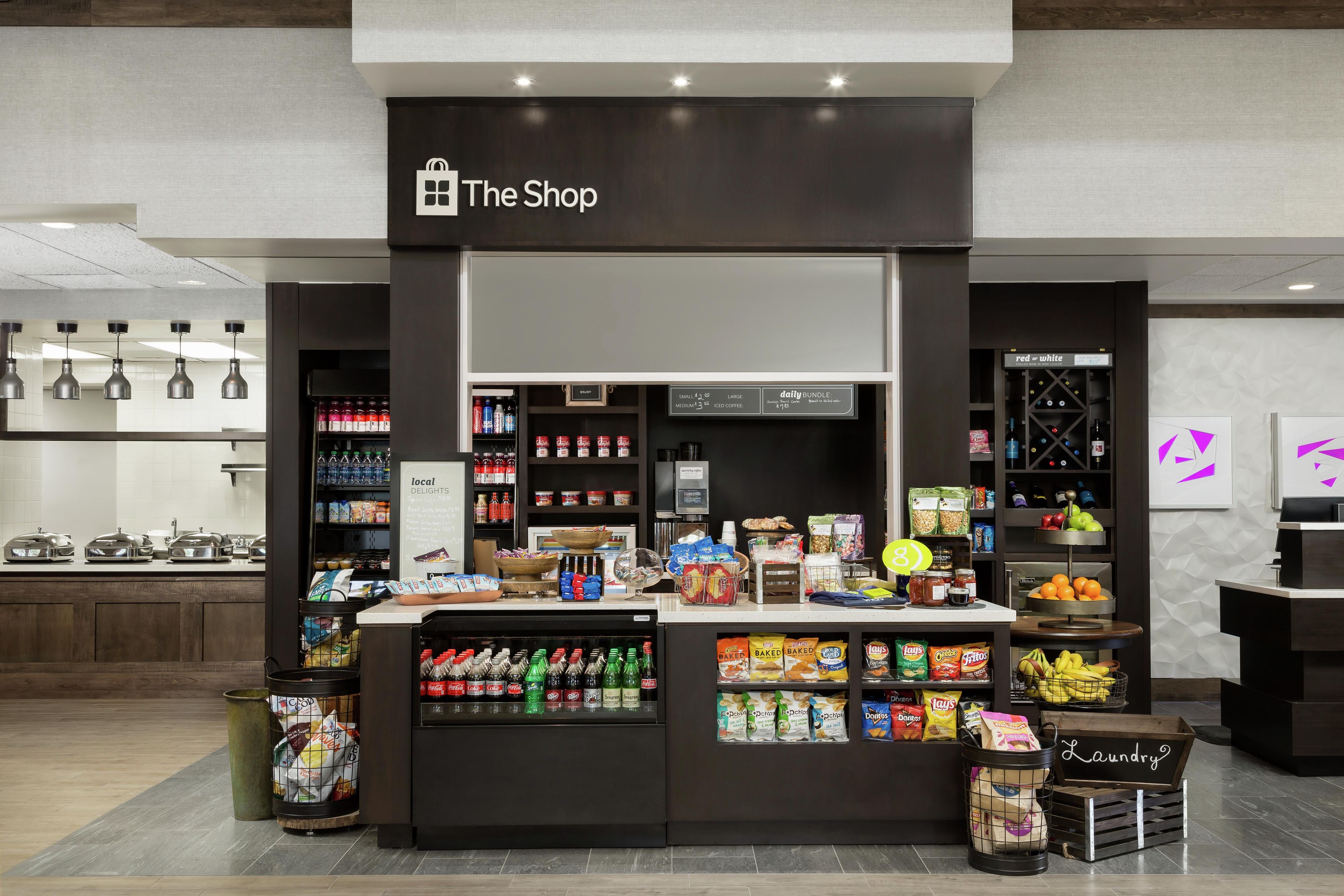 Una tienda llamada 'The Shop' con una variedad de bocadillos, bebidas y productos envasados.