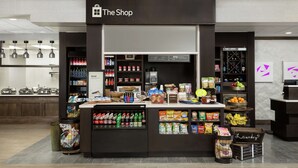 Una tienda moderna llamada 'The Shop' con una variedad de productos, incluyendo snacks, bebidas y artículos para el hogar.