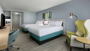 A hotel room with a double bed, a desk with a chair, a television, and a kitchenette.