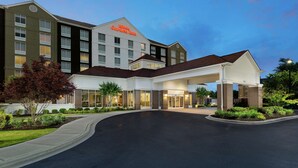 Un hotel de varios pisos con una entrada destacada y un camino de entrada ajardinado.
