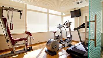 Un gimnasio con equipo de ejercicio, incluyendo una cinta de correr, elíptica y máquina de pesas.