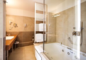 A modern bathroom with a bathtub, a glass-enclosed shower, a vanity with a sink, and a towel rack.