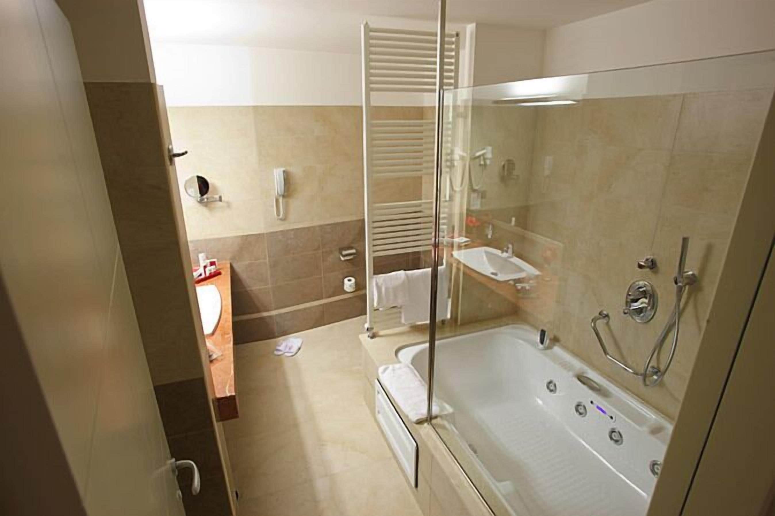 A modern bathroom with a glass-enclosed shower, a bathtub, and a vanity with a mirror.