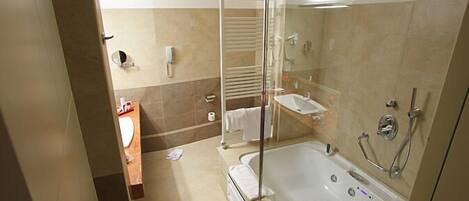 Un baño moderno con ducha de vidrio, una bañera y un lavamanos con espejo.