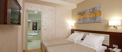 Habitación de hotel con dos camas, baño, televisión y un cuadro en la pared.