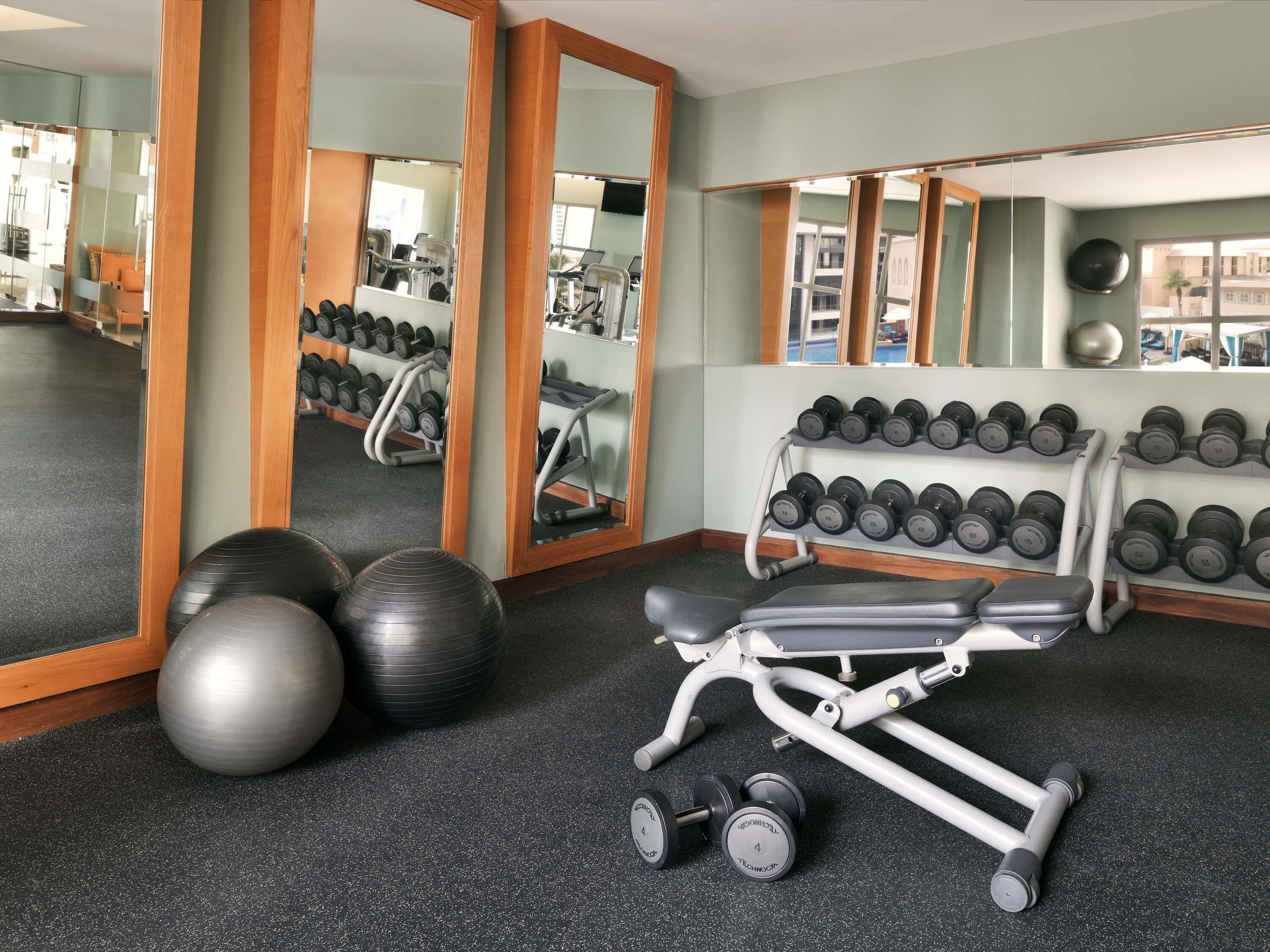A gym with exercise equipment, including dumbbells, exercise balls, and a bench.
