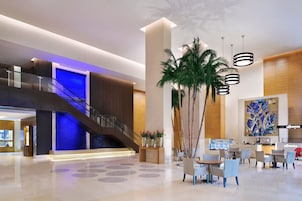 A modern lobby with a staircase, seating area, and a large abstract painting.