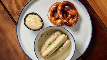 A plate with pretzels, a small bowl of sauce, and two boiled eggs garnished with chives.