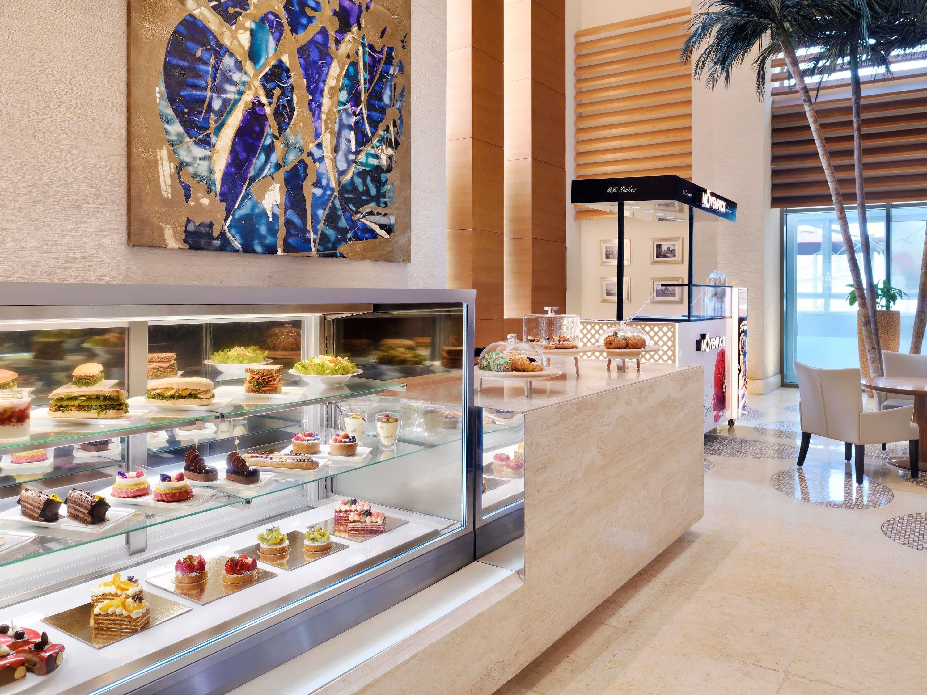 A hotel lobby with a dessert display, a reception area, and a large abstract painting.