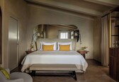 A bedroom with a bed, a bench, a bedside table, a mirror, and a wardrobe.