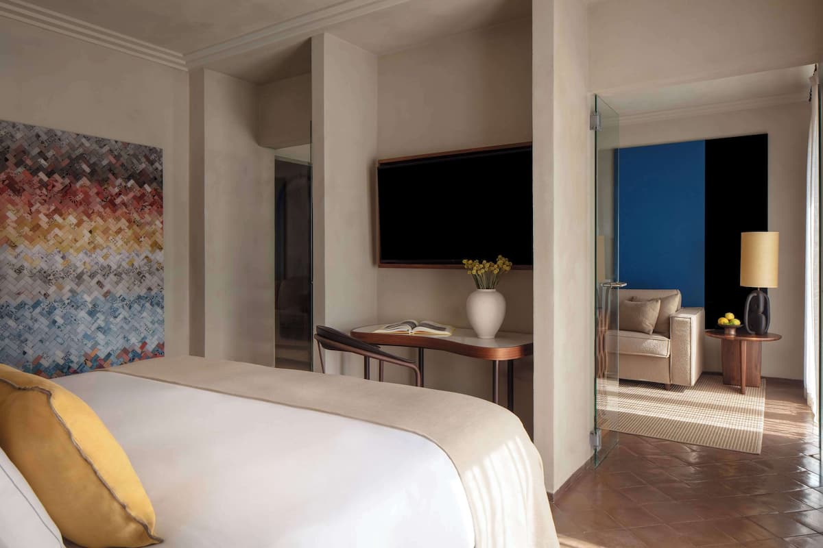 Een hotelkamer met een bed, een klein tafeltje met een vaas, een bank en een televisie.