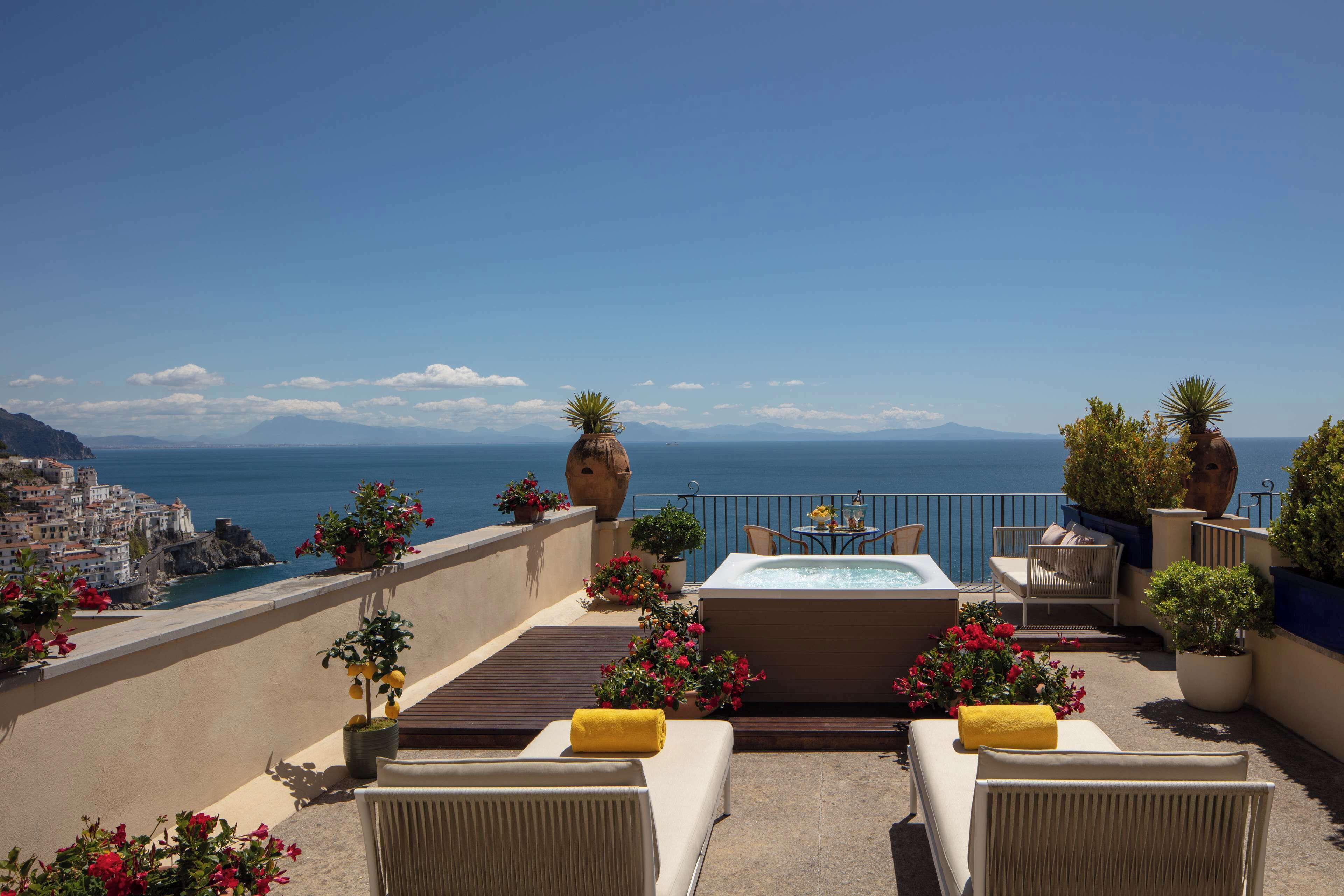 Une terrasse sur le toit équipée d’un jacuzzi, de chaises longues et de plantes en pot.