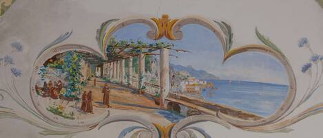 A ceiling fresco with a coastal scene, architectural columns, and a bridge.